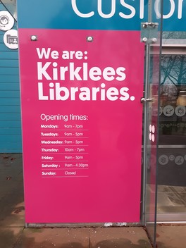 Large sign showing the opening times of Huddersfield Library