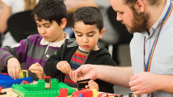 Image of male staff member and 2 children building with Lego