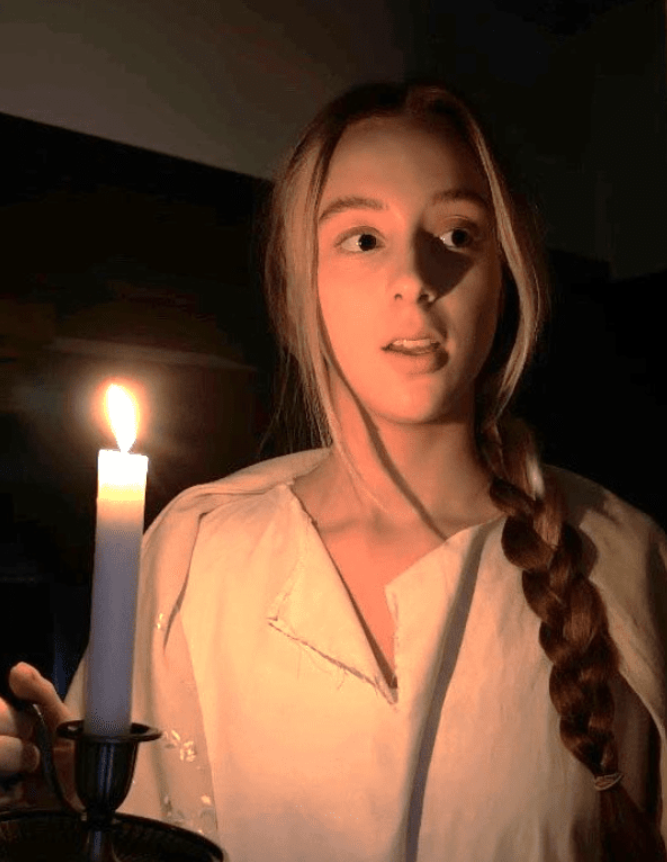 Image of girl in nightdress with candle looking scared