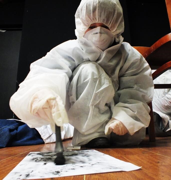 Image of person in CSI suit dusting for fingerprints