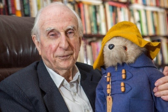 Image of Michael Bond holding a Paddington Bear toy