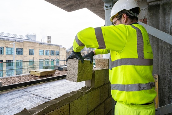 Image of builder laying a brick at the new Huddersfield Library