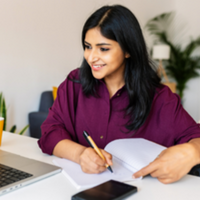 Woman sat at desk looking at laptop and smiling