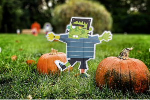 Picture of a halloween character on some grass next to pumpkins
