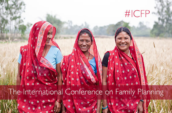 Three women wearing red saris stand in a field of wheat. The International Conference on Family Planning #ICFP