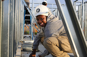 AmeriCorps member in a hardhat building a house