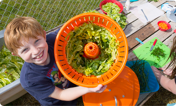 A Colorado elementary school student shows off fresh lettuce grown by students in the school’s garden. 