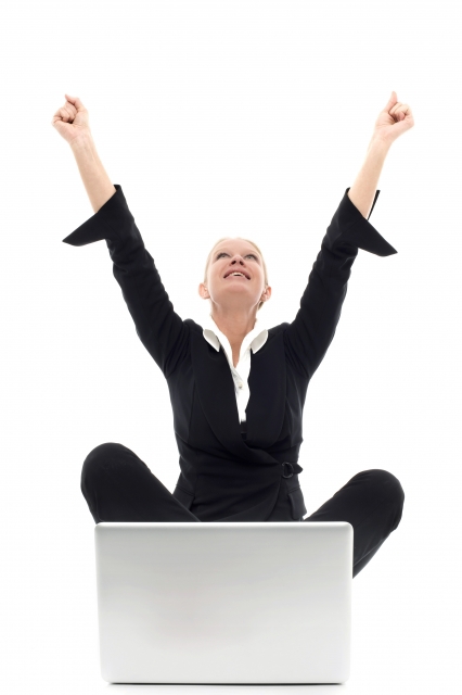 Woman celebrating with hands in the air in front of her laptop