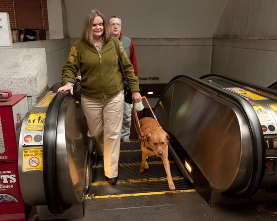 Woman coming up WMATA escalator with service dog