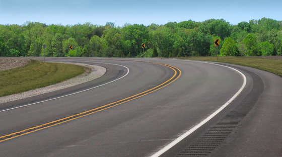 Curve on a highway utilizing signs and rumble strips to minimize roadway departures.