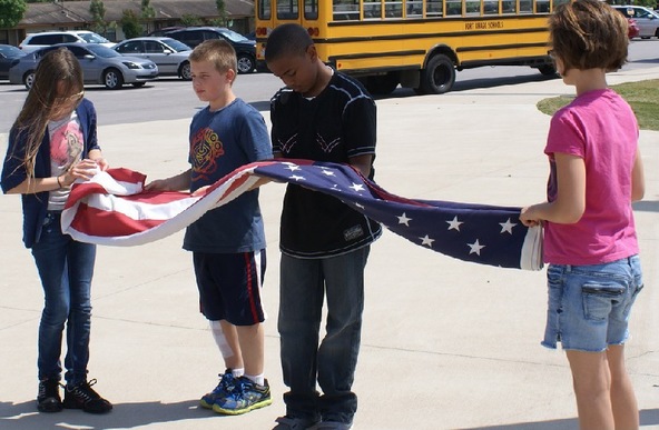 Students at a DoD school fold the U.S. flag