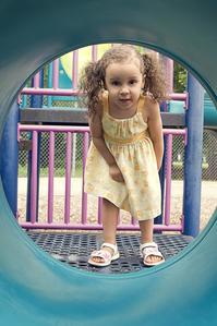 Child in playground looking through tunnel