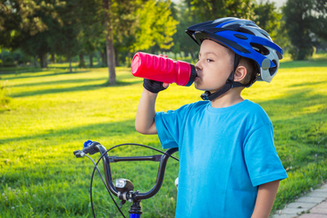 boy pausing from riding bike to drink water