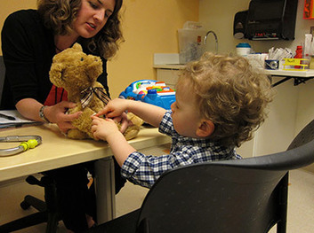 Two-year old participant in The Environmental Determinants of Diabetes in Youth (TEDDY) consortium with teddy bear and nurse..