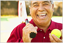 Man holding a tennis racquet and smiling.
