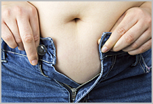 A person trying to fit in their jeans.