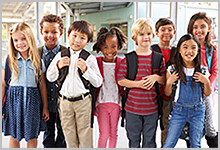 A group of children standing outside of school.