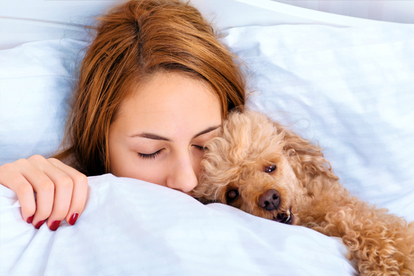 A woman sleeping with a dog.