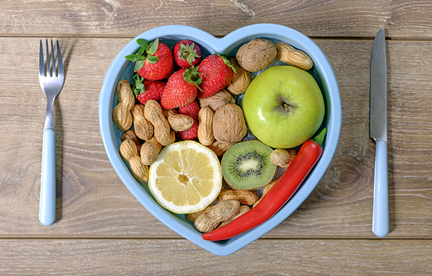 Silverware and a heart-shaped bowl full of heart healthy foods.