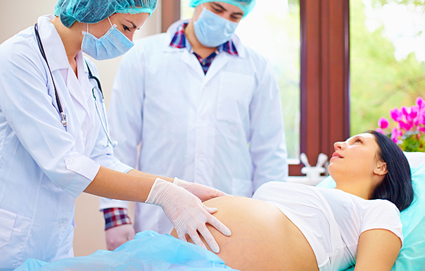 Doctors examining the abdomen of a pregnant woman during childbirth.