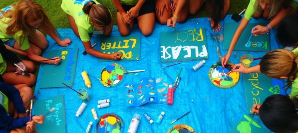 Students painting signs to encourage people to stop littering and to recycle.