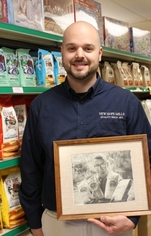 Doug Weed holds photograph of his grandfather, Leland Weed, in the New Hope Mills factory store in Auburn, NY.