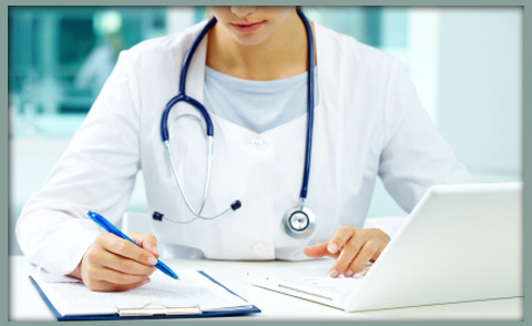 Image of a female doctor or nurse conducting paper and electronic reconciliation of patient information.