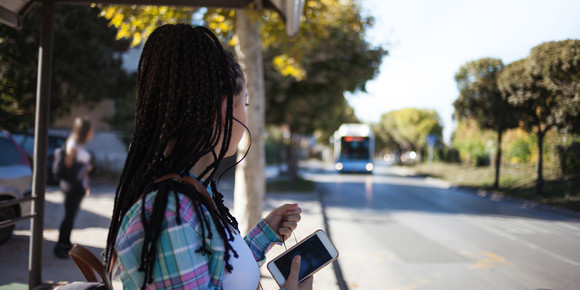 Woman holding smartphone, while waiting for bus