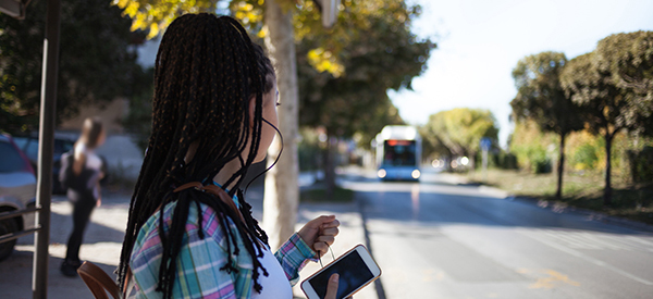 Woman waiting for bus while holding smartphone