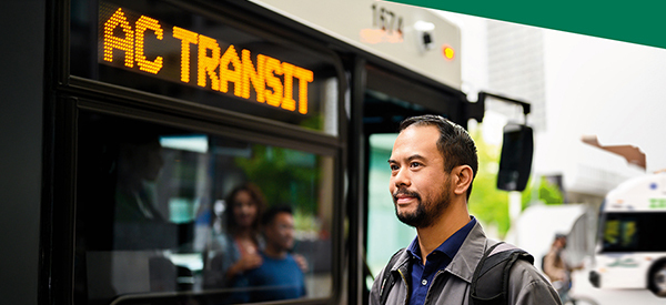 Man standing in frotn of an AC Transit bus