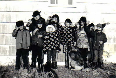 ten kids with a dog wave at the camera