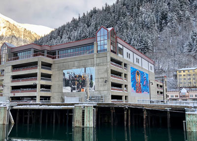 Crystal Worl’s new mural of Elizabeth Peratrovich and the older mural of White settlers arriving by steamship