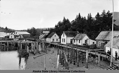 wooden buildings and walkway on pilings along water