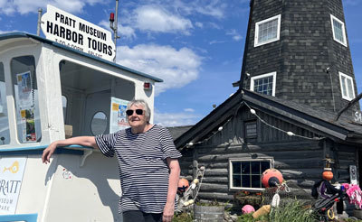 Linda Rowell poses in front of the Salty Dog Saloon, at the Homer Harbor History Tour kiosk.