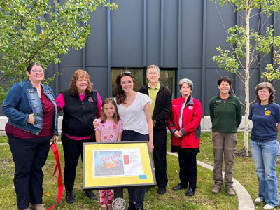 Sara Saxton, Jeanne Troshynski, Brooke Hartman, Glenda Ledford, Elizabeth Ripley, Carlyn Lambert, and others stand in front of Storywalk display