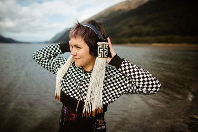 person in front of channel in southeast alaska wears headphones featuring weaving