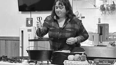 Kuskokwim Consortium Library Director Theresa Quiner instructs her students how to safely position a hot dutch oven lid