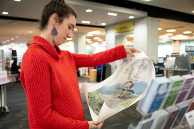 Molly Roache looks at the free print she picked out from the Alaska Collection on Thursday.