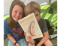 two kids hold book up in tent: Field Guide to the Pacific Salmon
