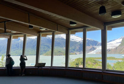 Visitors take photos of Mendenhall Glacier near Juneau in summer 2022 from inside the Mendenhall Glacier Visitor Center.