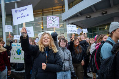 Students at Career Tech High School in Wasilla wave protest signs at honking cars on Tuesday.