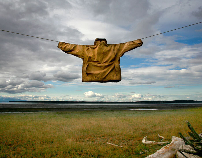 tan jacket hangs on line with arms extended against big blue sky with clouds and expansive horizon