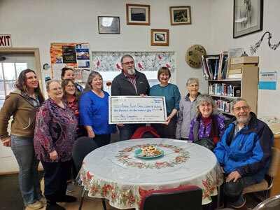 Anchor Point library staff gather around Homer Foundation executive director Mike Miller, who holds a grant check