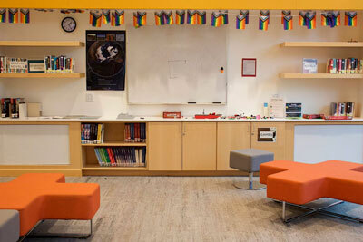 A row of rainbow flags are displayed above the bookshelves in the teen room at the Mendenhall Valley Public Library.