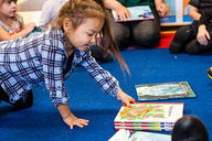 a young child reaches for a book