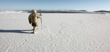 an Inuit hunter prepares to test the safety of sea ice near Sanikiluaq, Nunavut, with a harpoon