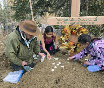 At the grave of Lucky Pitka McCormick, her granddaughter and great-great-grandchildren place candles and stones