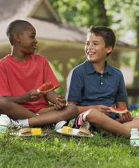 Two kids enjoying summer meals outdooors
