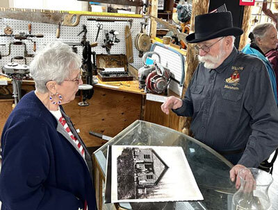 Mat-Su Borough Mayor Edna Devries listens as Jim Huston talks history at the re-dedication of the Willow Historical and Wildlife Museum.