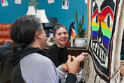 Melina Meyer and Laine Rinehart laugh while weaving the bottom fringe of the Chilkat Pride robe on Saturday